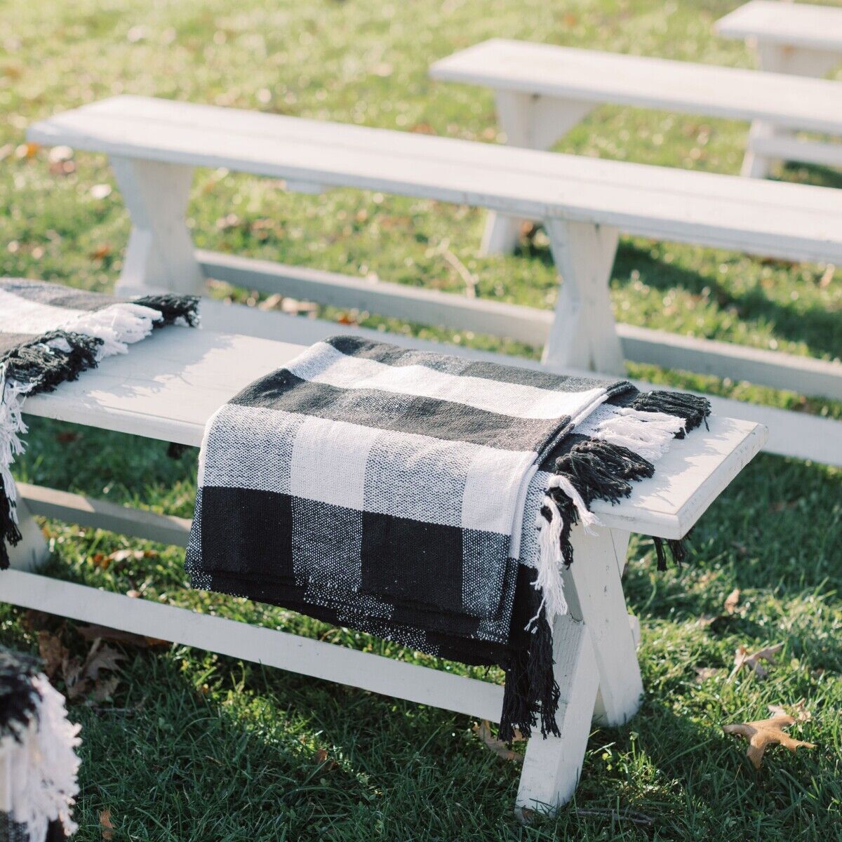 Fall weather wedding ceremony with black and white plaid blankets on white benches