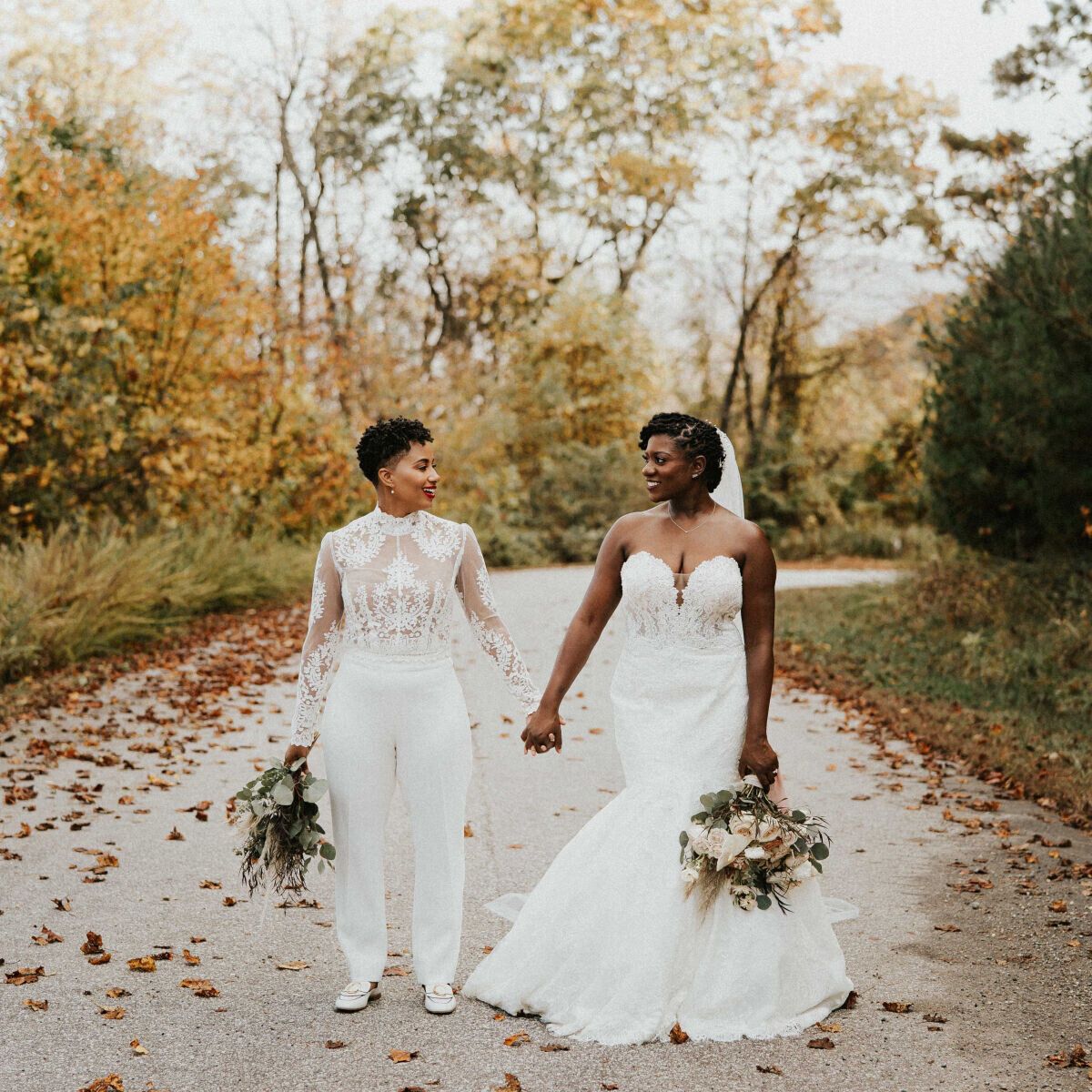 Brittany and Adrienne holding hands on a fall forest road in Asheville, North Carolina