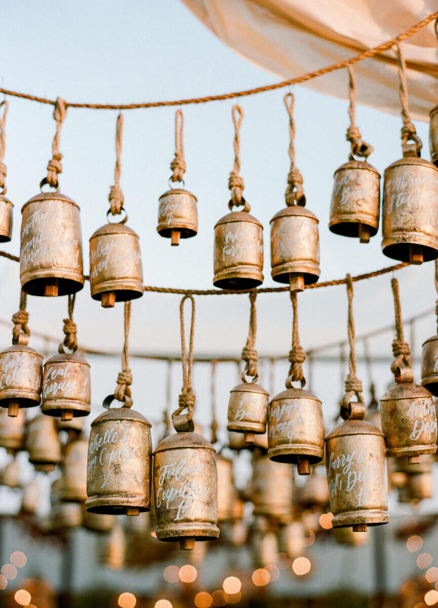 Instead of traditional escort cards, calligraphed bells were hung at the entrance to an earth tone wedding reception tent.