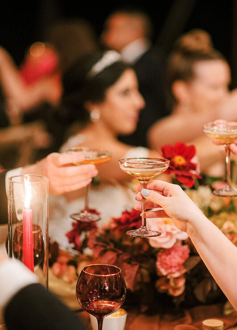 A newlywed couple and their guest clink glasses during a toast at their tented wedding reception.