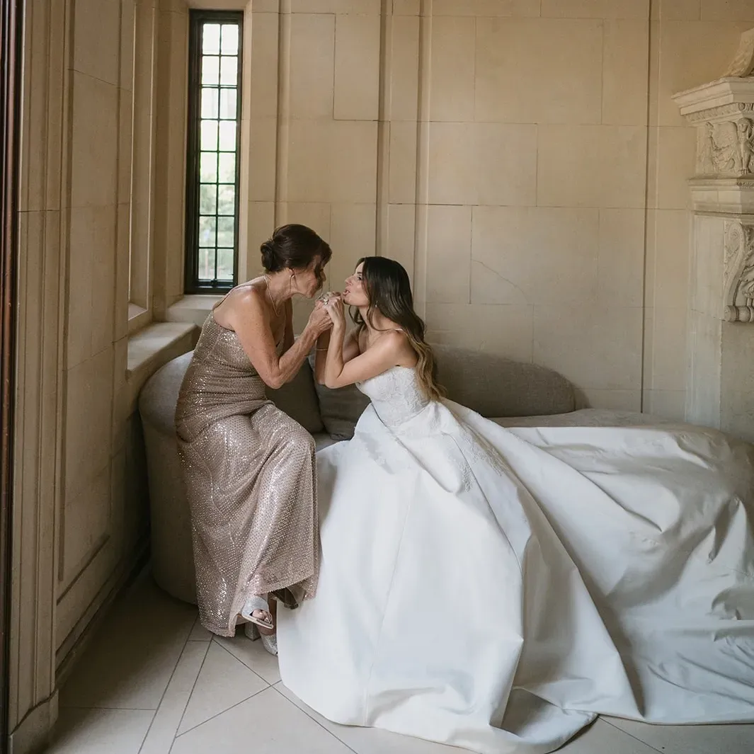 Mother of the bride in a metallic gown, holding hands with her daughter, photographed by Josie Brooks Photography