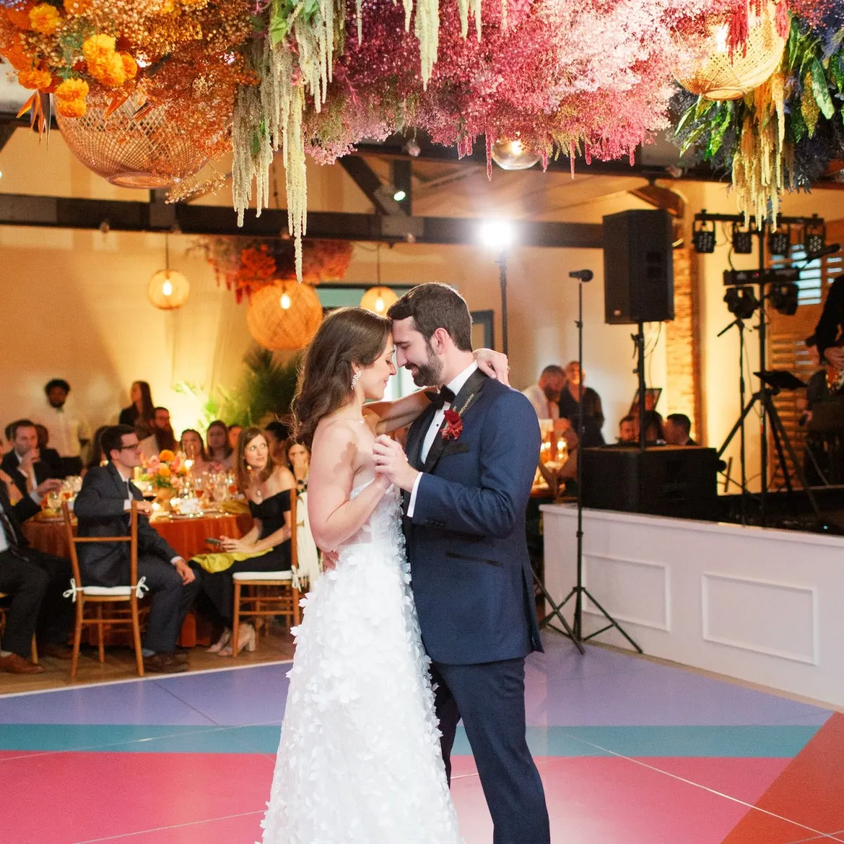 Newlyweds dance on a colorfully patterned dance floor during their art-inspired wedding reception.