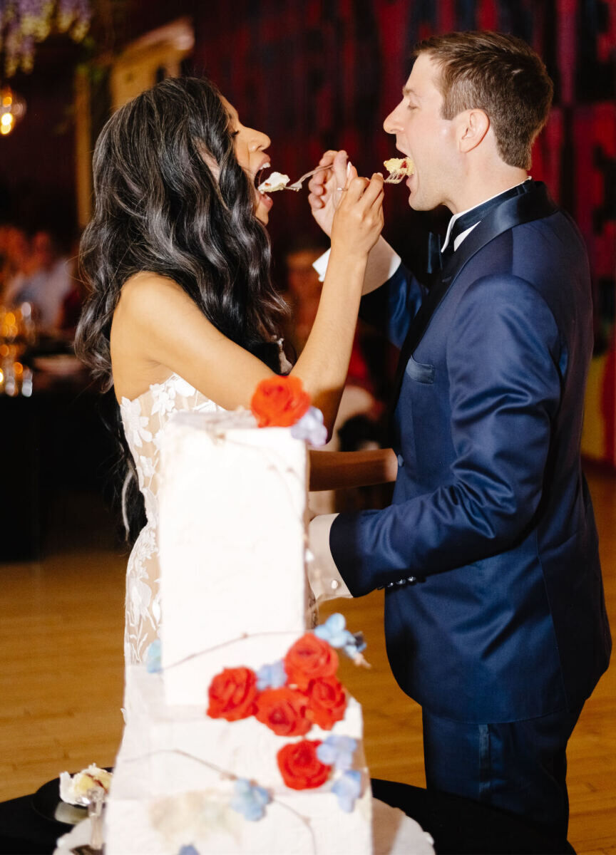 A bride and groom feed each other cake during their art museum wedding reception at MASS MoCA.