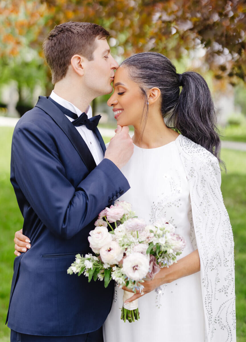 For her intimate church ceremony, a bride wore a full ponytail and a caped wedding dress.