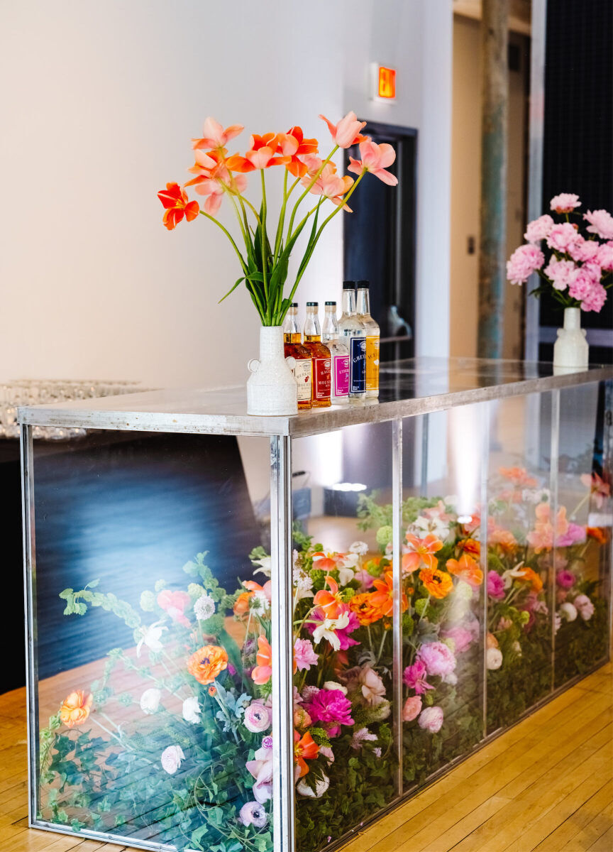 A transparent bar was filled with fresh flowers and used to serve beverages during the reception of an art museum wedding.