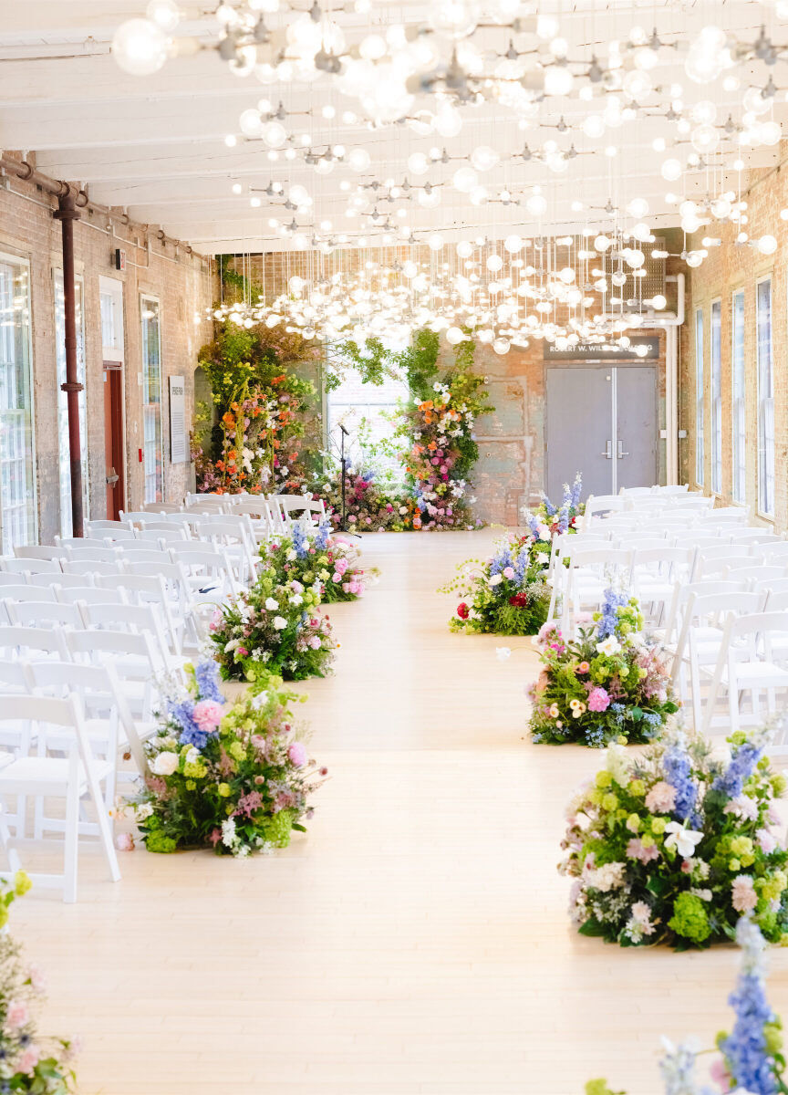 An installation of lights above the ceremony space was mimicked in the florals along the aisle, which lead to a flower-filled corner where the couple would marry during their art museum wedding ceremony.