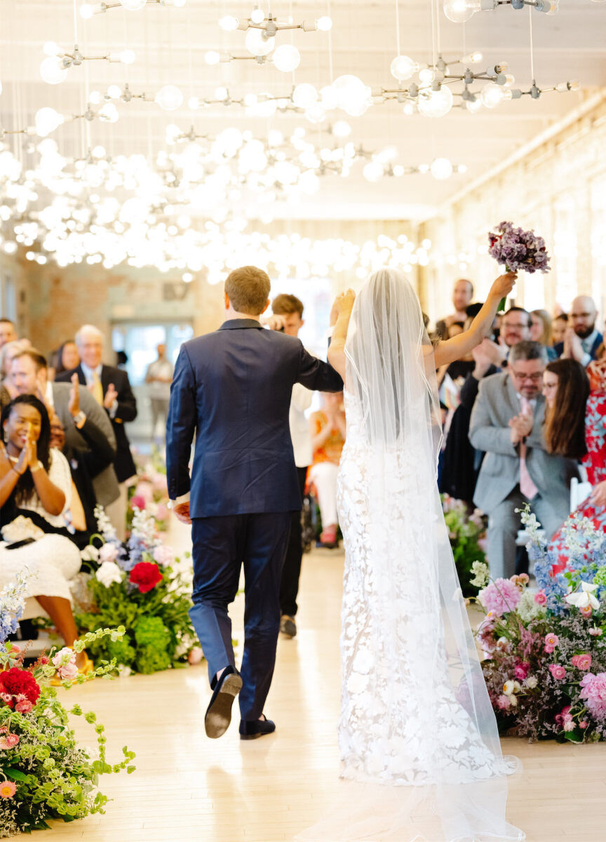 Newlyweds excitedly recess up the aisle at the conclusion of their art museum wedding ceremony.