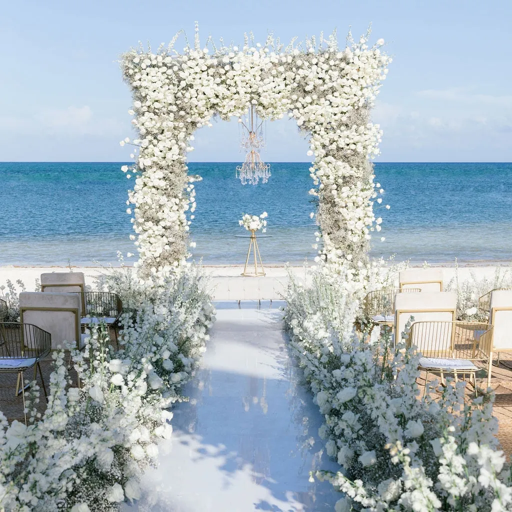 Beach wedding ceremony set up featuring wedding arch of all white blooms