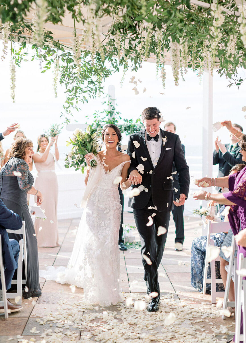 Just married wedding couple walking up the alter being showered with flower petals thrown by guests celebrating them