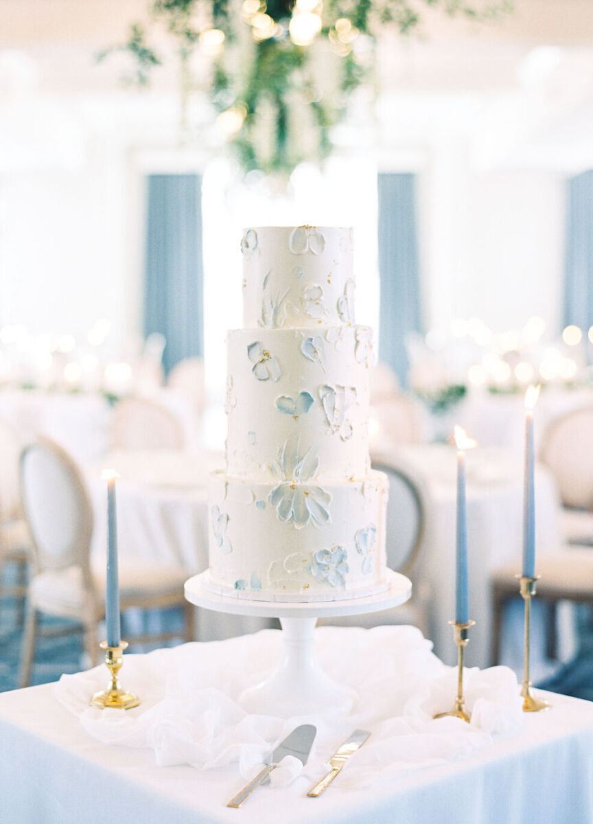 White and blue wedding cake displayed with matching blue candles