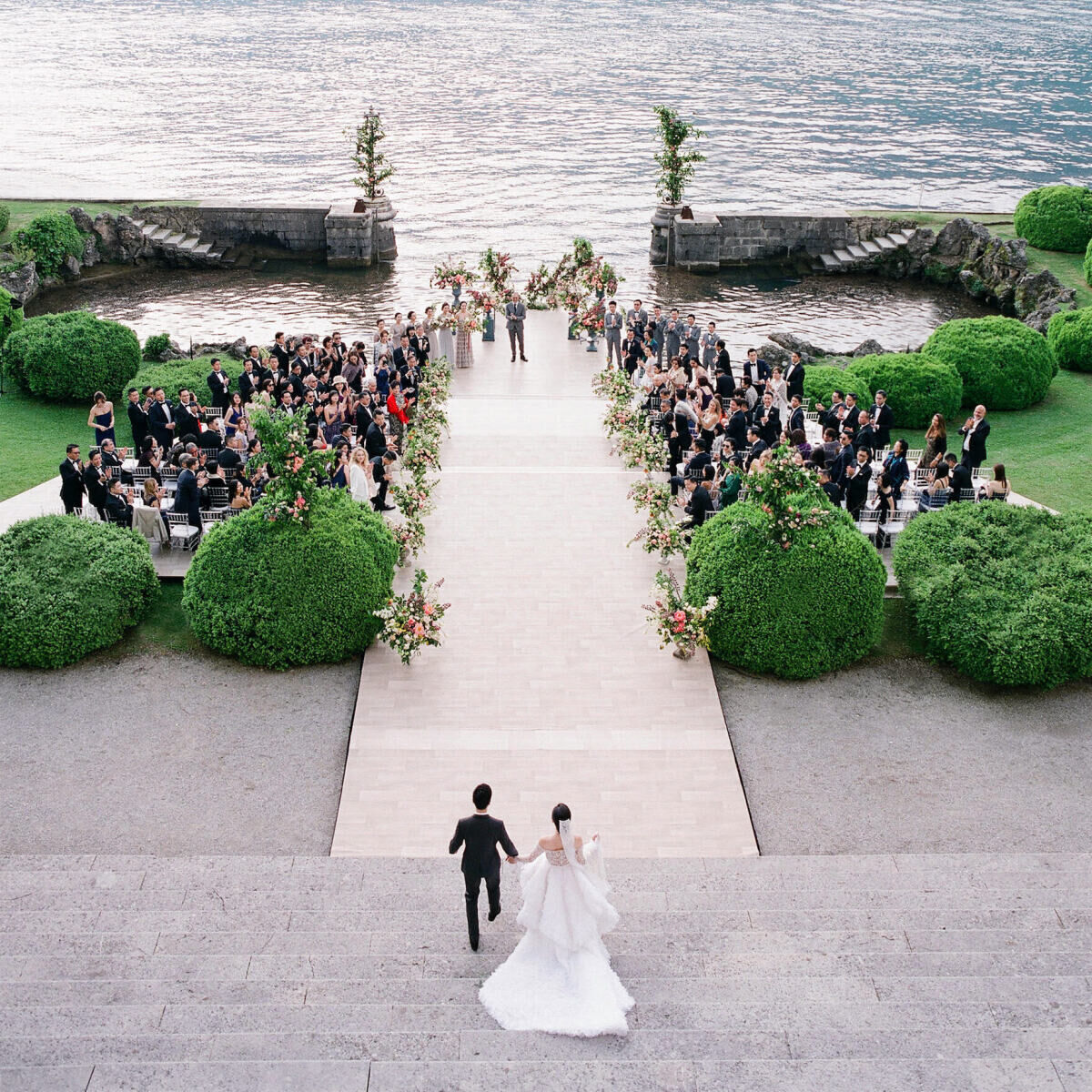 Italian waterfront wedding ceremony setup, bride being escorted down the aisle.