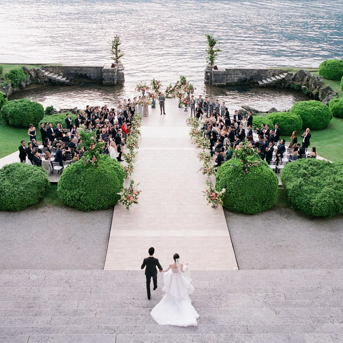 Italian waterfront wedding ceremony setup, bride being escorted down the aisle.