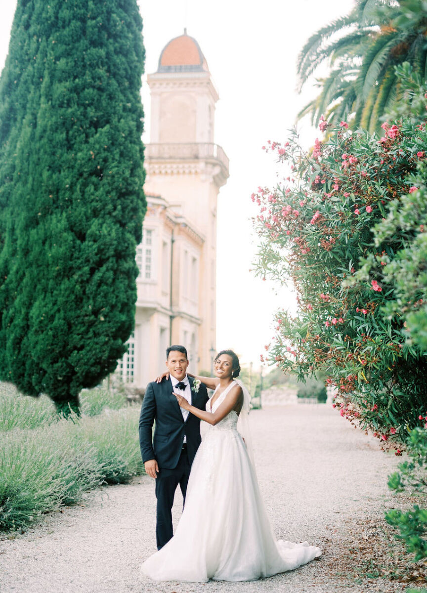 Castle Wedding Venues: A wedding couple smiling with a view of a French chateau's tower in the background.