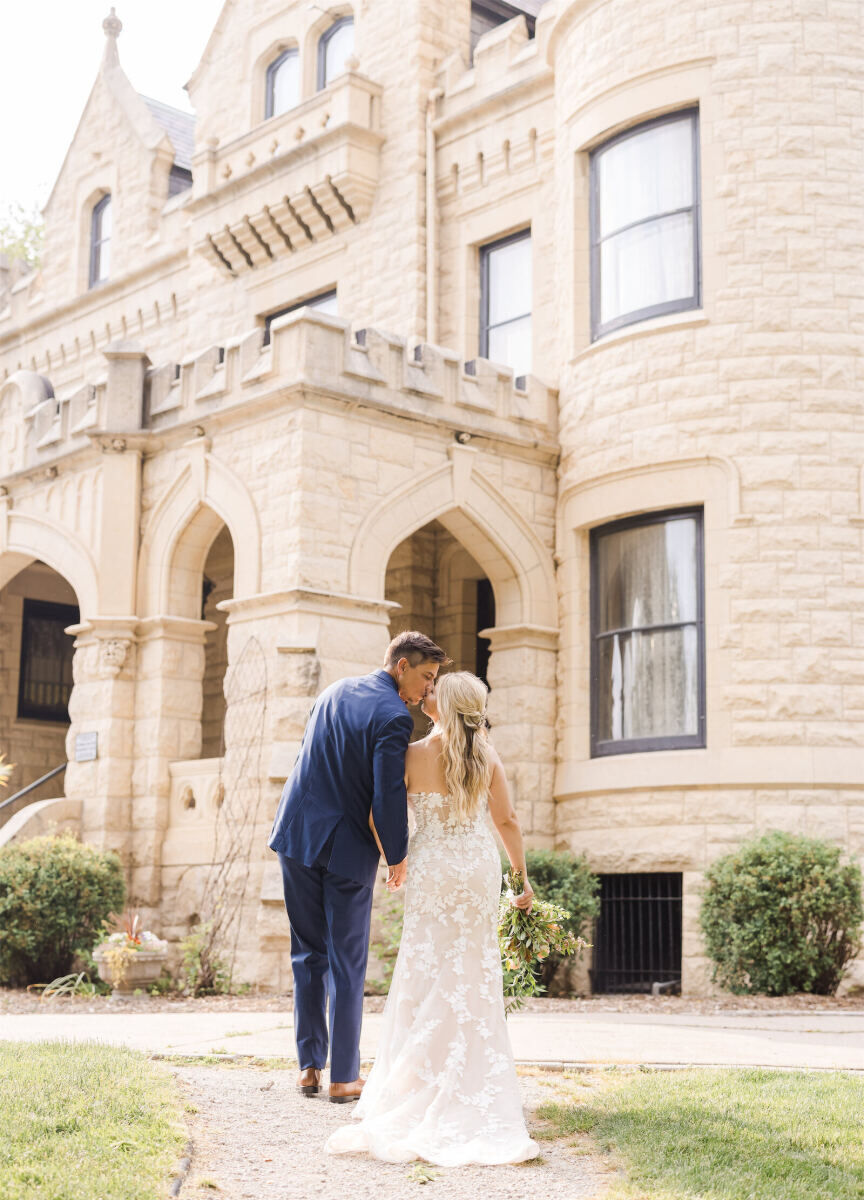 Castle Wedding Venues: A wedding couple kissing in front of a stone castle property in Omaha, Nebraska.