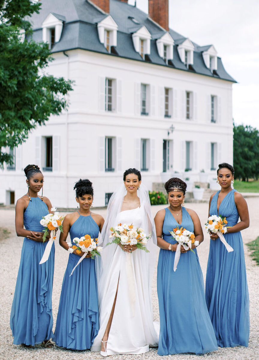 Castle Wedding Venues: A bride posing with her four bridesmaids, who are all wearing blue dresses, with a white French chateau in the background.