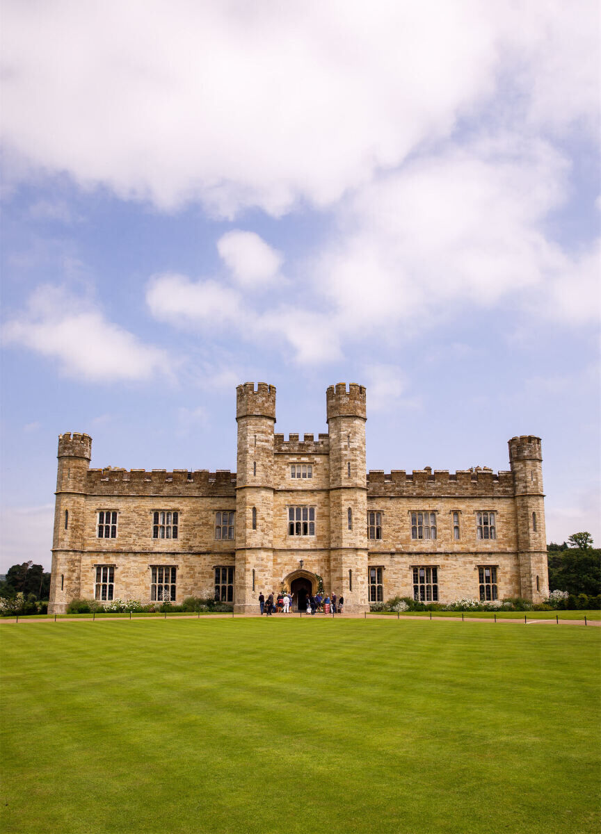 Castle Wedding Venues: An English castle with a vibrant green lawn and blue skies overhead.