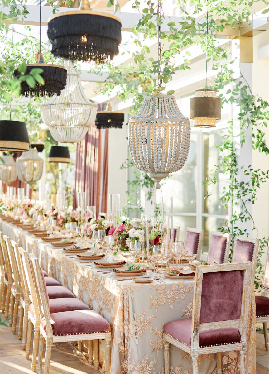 Ceiling Wedding Decor: Varied chandeliers with different threads, beads, and other boho elements hanging over a long rectangular table.