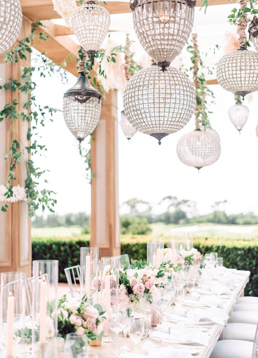 Ceiling Wedding Decor: Crystal-covered chandeliers and greenery hanging over an outdoor reception table in Southern California.