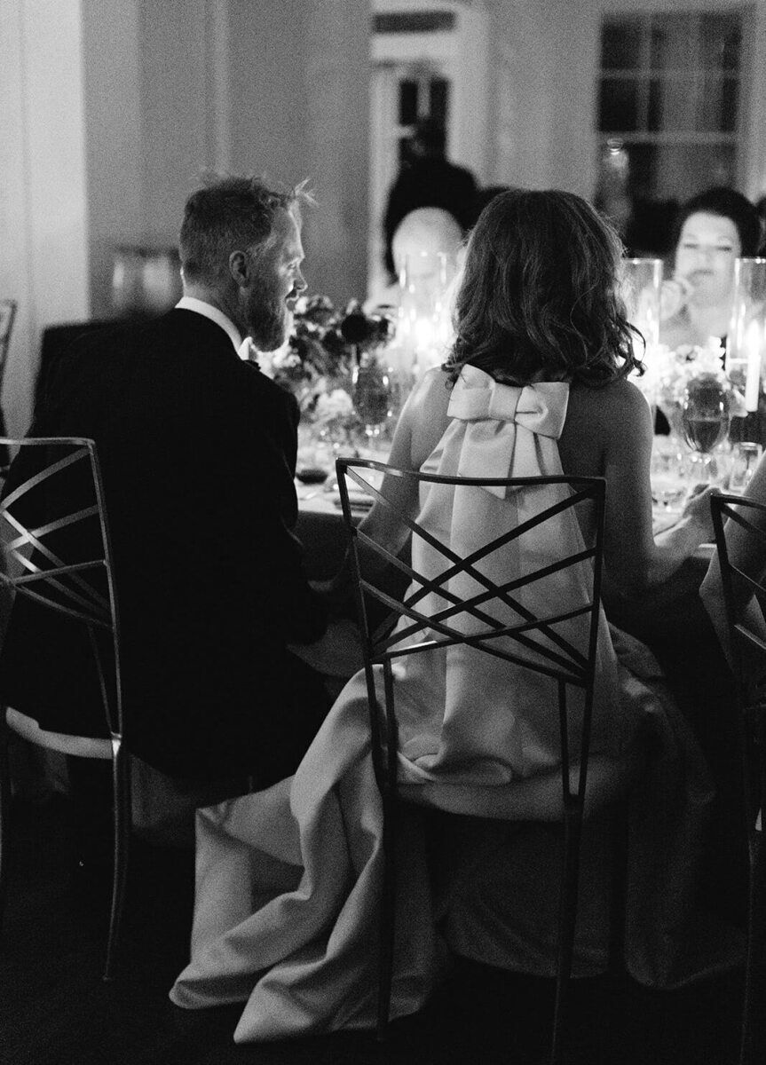 A groom and bride enjoy dinner by candlelight at their wedding reception.