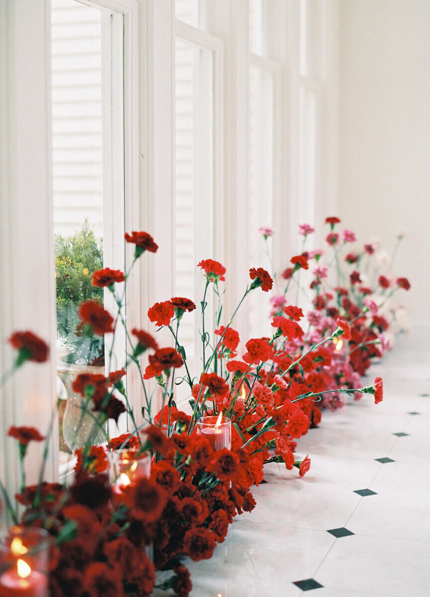 A wedding reception hallway decorated with a gradient of colorful flowers and glowing candles.