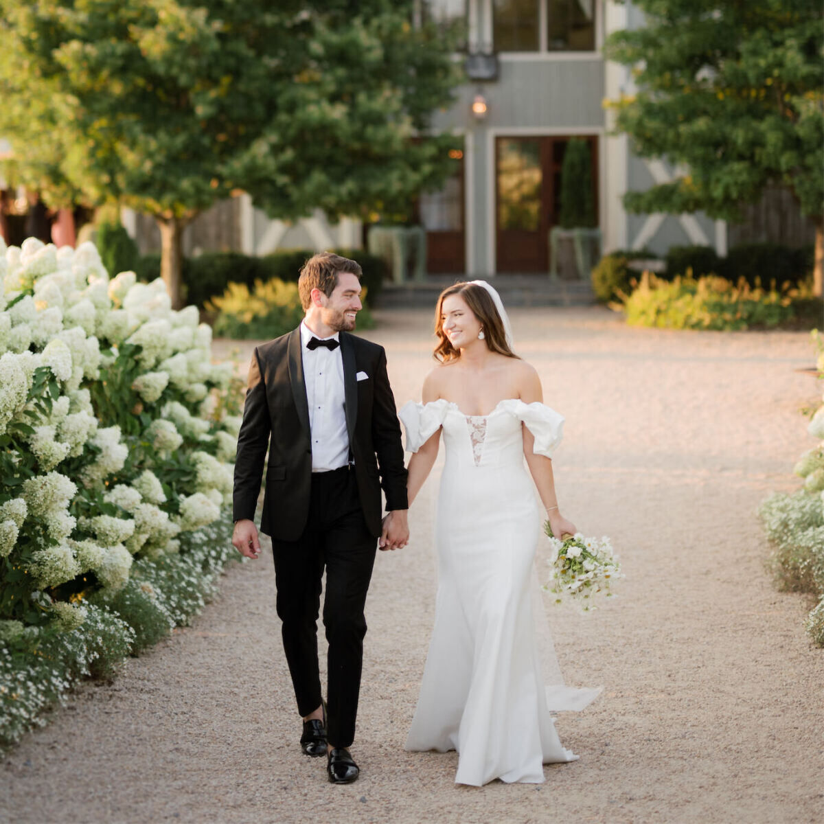 Wedding couple strolling hand-in-hand along a garden path in front of their countryside wedding venue, Pippin Hill Farm & Vineyards