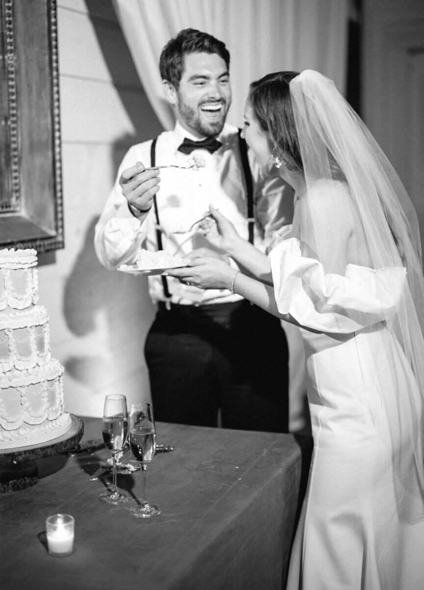 A pair of newlyweds cut their wedding cake and feed it to one another at their cottagecore wedding reception.