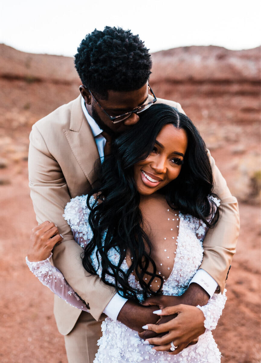 A groom embraces his wife at their desert wedding in Utah.