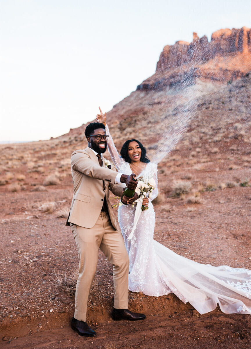 Newlyweds pop champagne at their desert wedding in Moab, Utah.