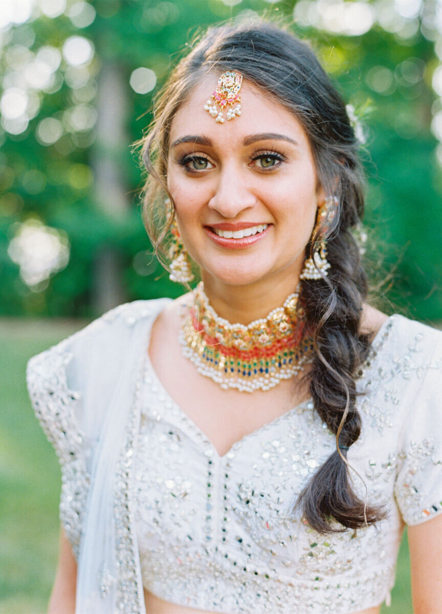 A close-up of a bride with a tousled side braid and natural makeup at her Sangeet during her destination Indian wedding.