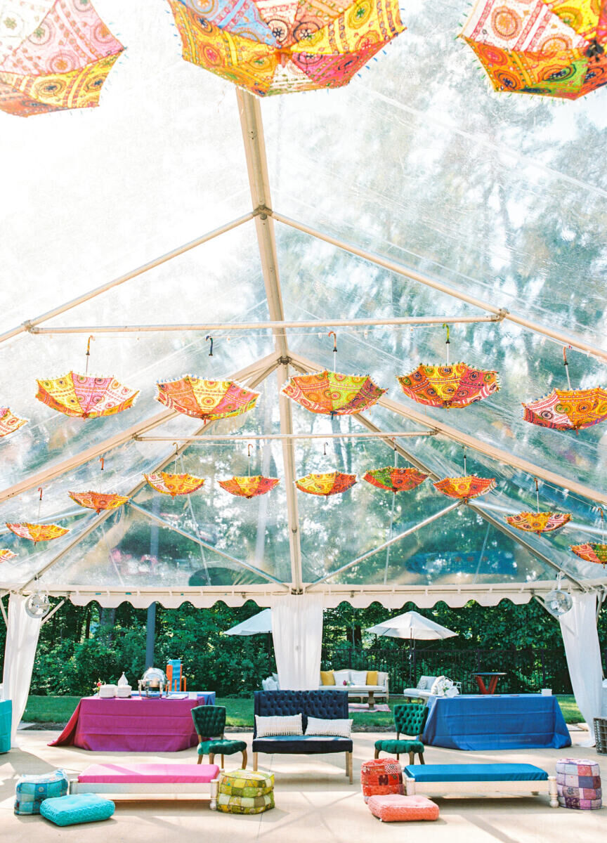 The second day of this destination Indian wedding weekend included a Sangeet, designed in jewel tones, with colorful parasols hanging from the top of the clear tent.