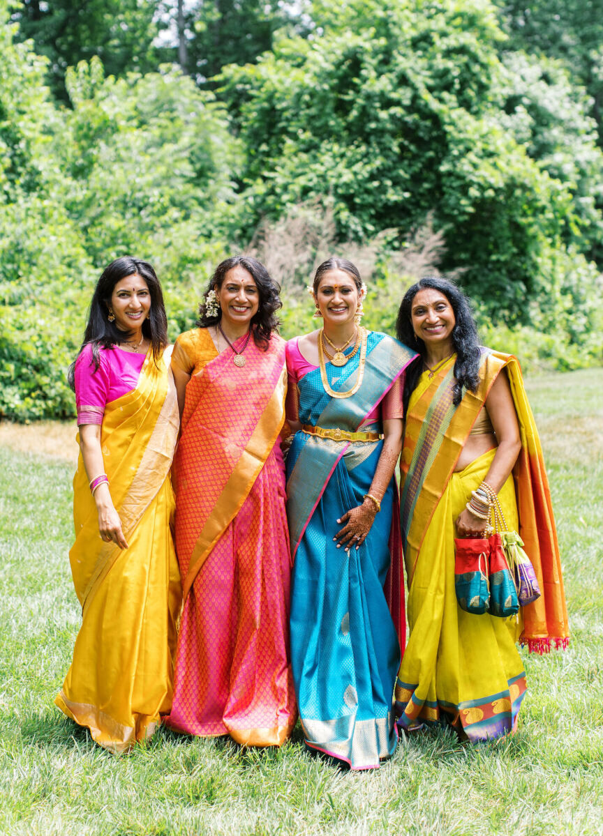 A bride surrounded by her loved ones, all in vibrant, traditional Indian attire, at her destination Indian wedding weekend.