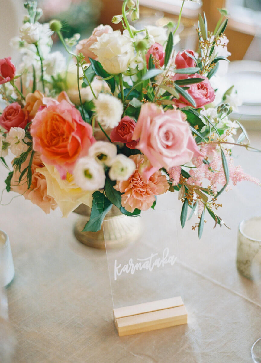 Pink and white floral centerpieces decorated the reception tables at this destination Indian wedding, with calligraphed signage guiding guests to their specific tables.