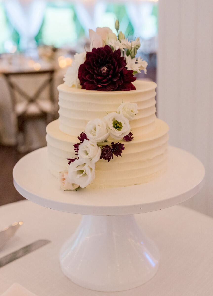 A simple, two-tier wedding cake was decorated with fresh flowers at an elevated garden wedding reception in Vermont.