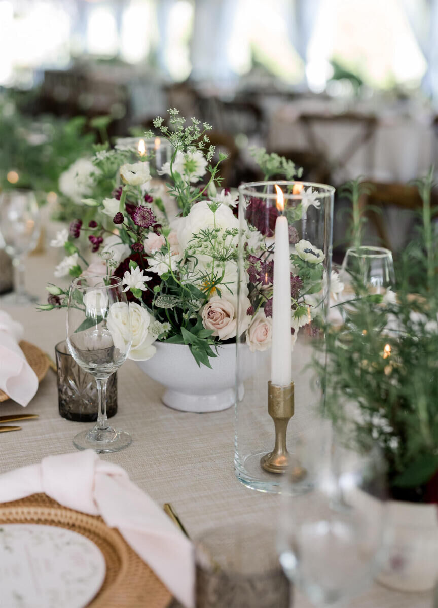 Footed bowls held arrangements of astrantia, roses, Queen Anne's lace, and dahlias at an elevated garden wedding reception.