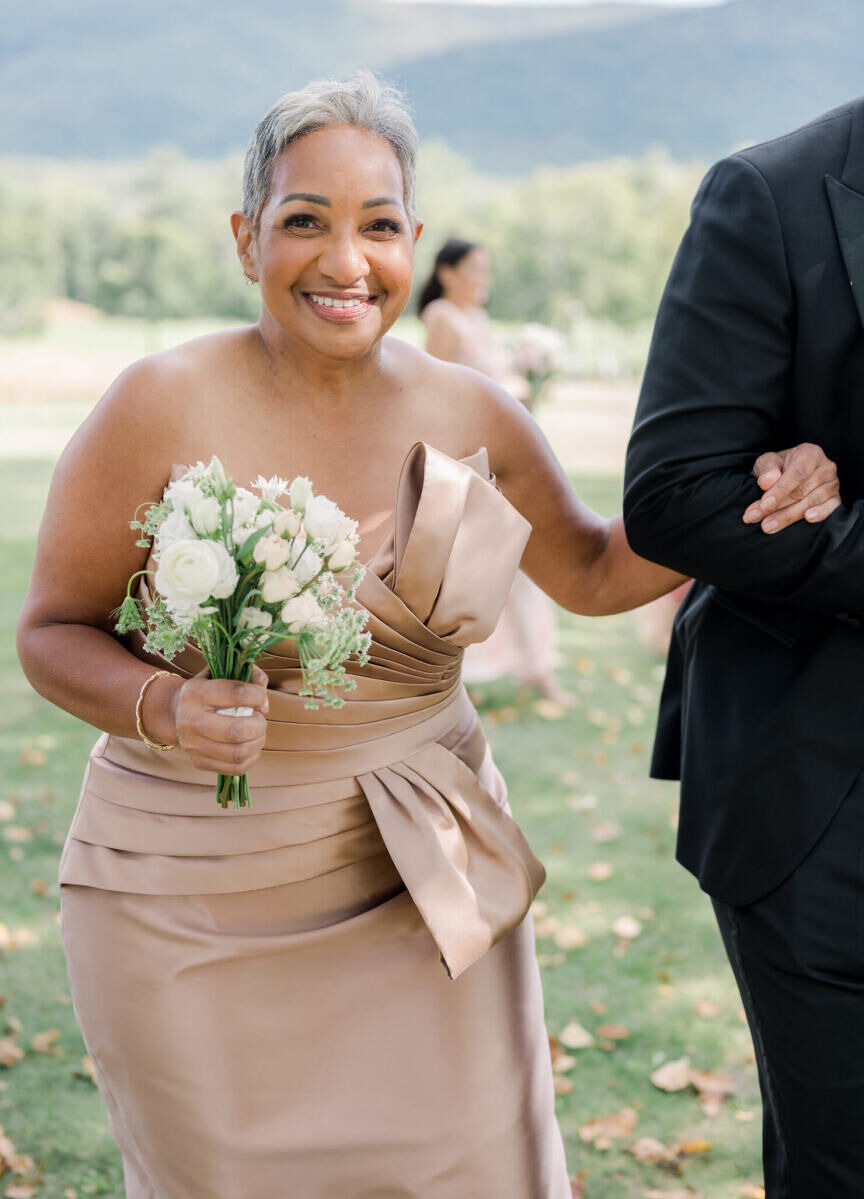 The mother of the groom is all smiles as she holds her bouquet at her son's elevated garden wedding.