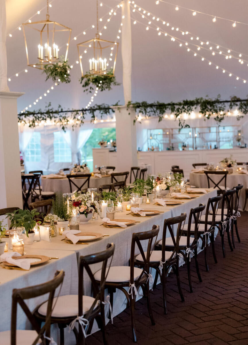 The tent of Hildene was decorated with cross-back chairs, wicker chargers, smoky stemware, and strands of bistro bulbs for an elevated garden wedding reception.