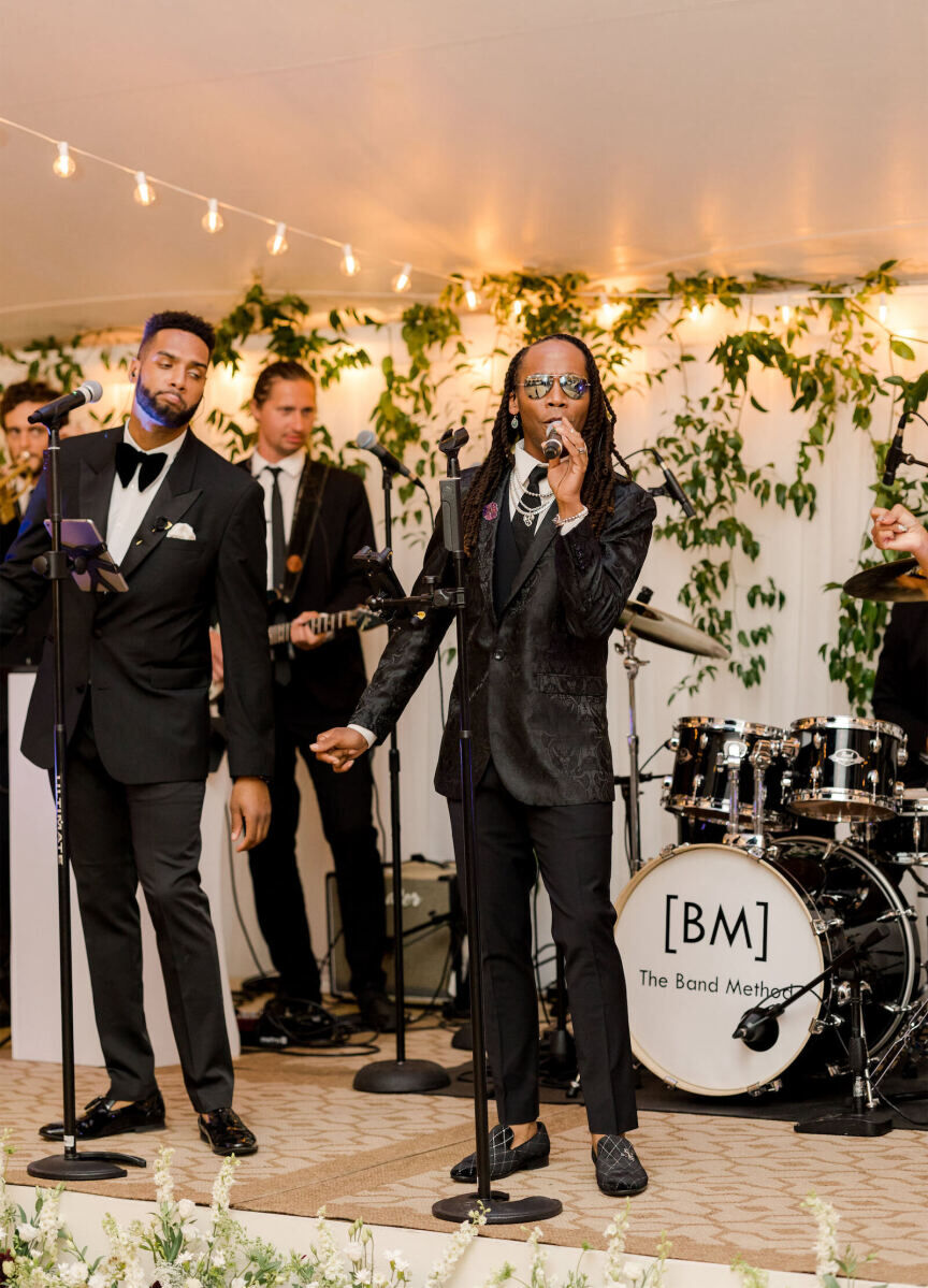 At an elevated garden wedding reception, the band performed in front of a wall of drapery and greenery.