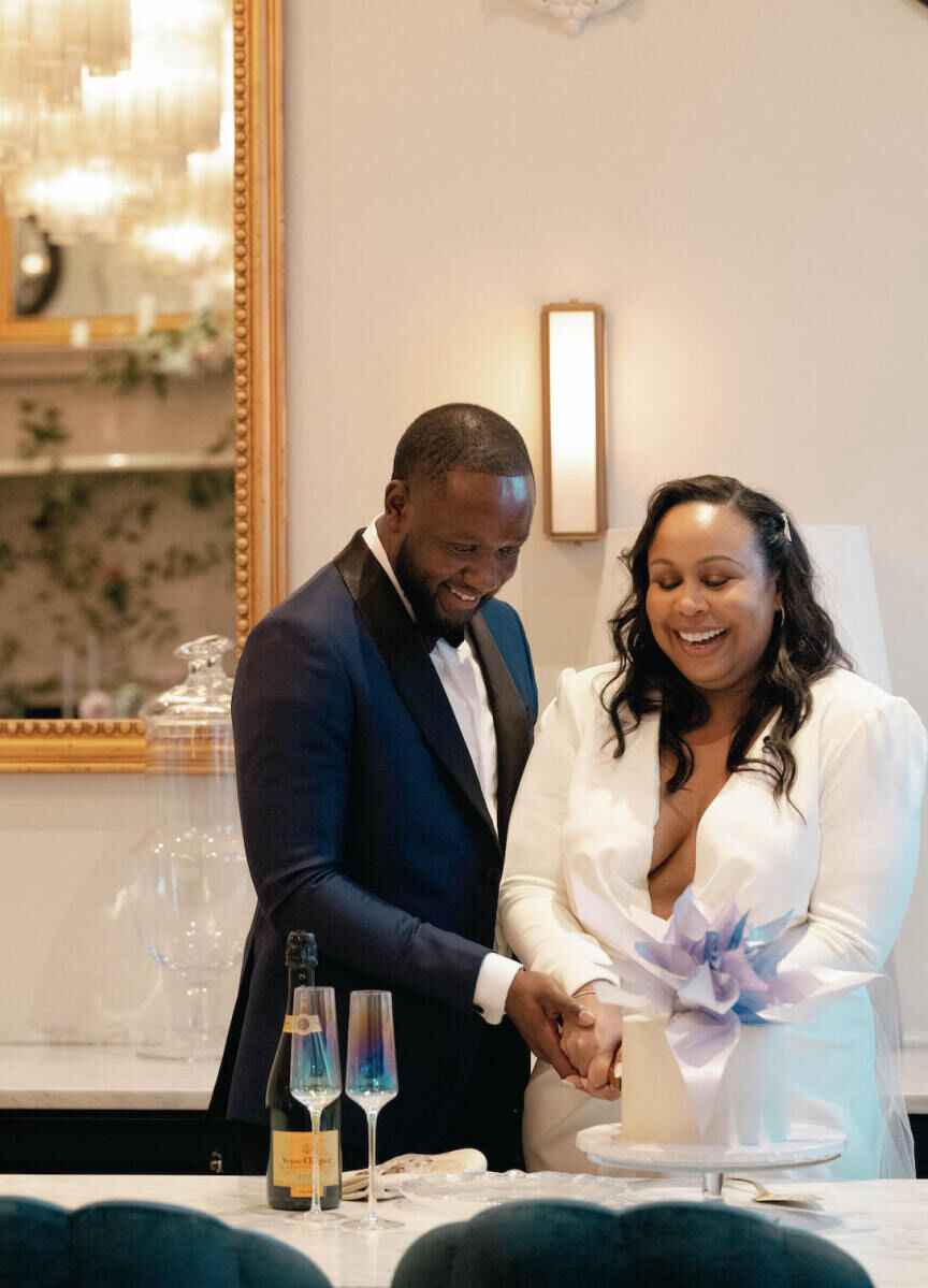 Elopement Wedding: A pair of newlyweds joyfully cut into their single-tier wedding cake during their weekday elopement.