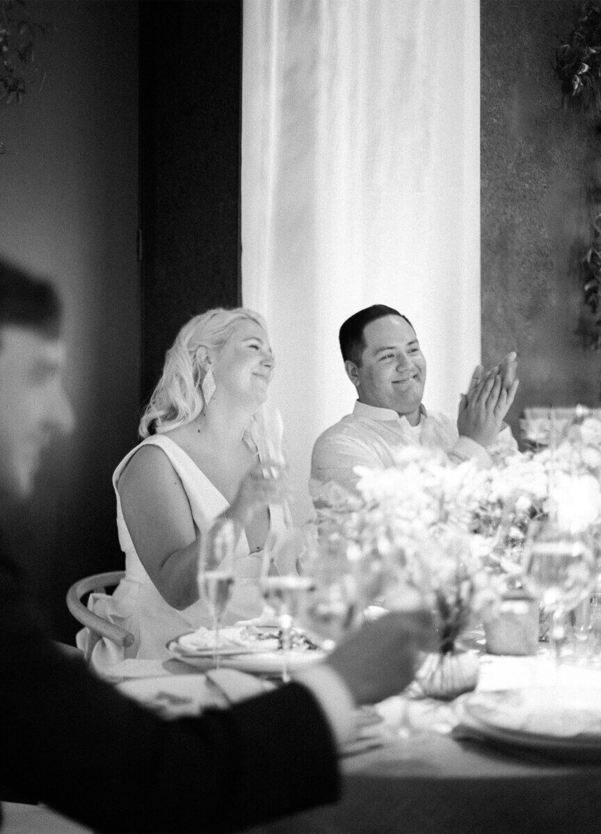 Newlyweds applaud during a speech recited during the reception of their enchanted waterfront wedding.