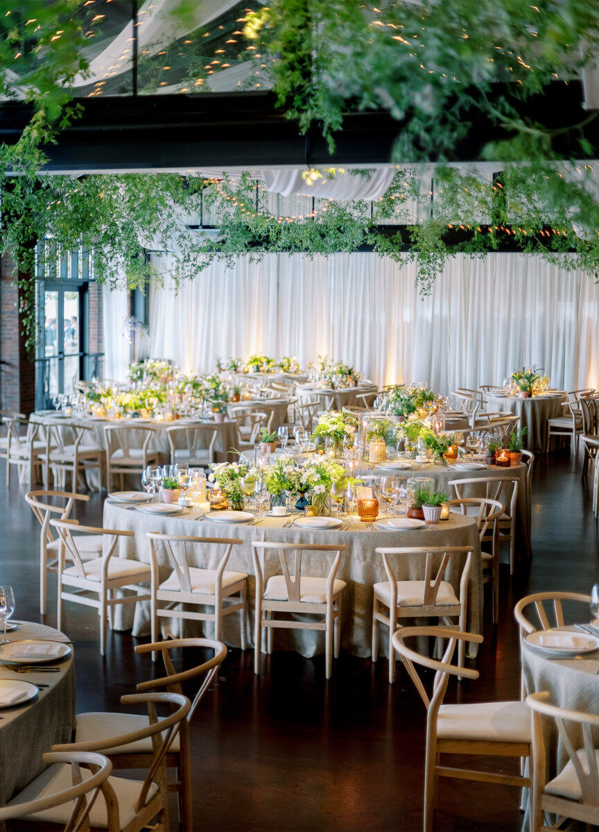 An enchanted waterfront wedding included an indoor reception set with oval tables and wishbone chairs.