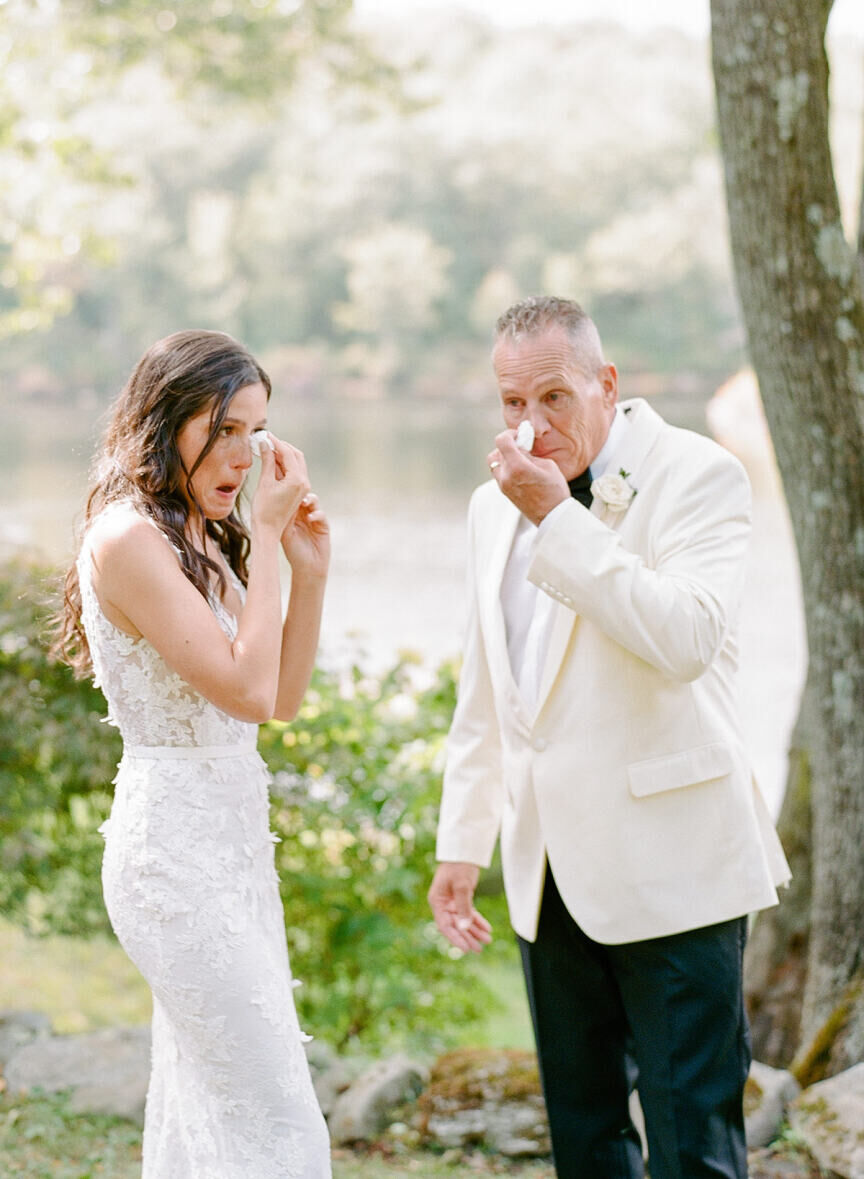 First Look Photos: A bride and her father wiping their tears with tissue on the wedding day.