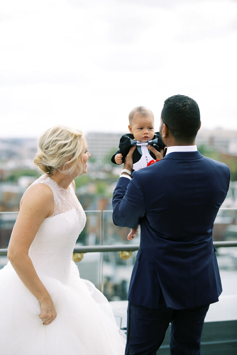 First Look Photos: A bride and groom looking at their baby on their wedding day.