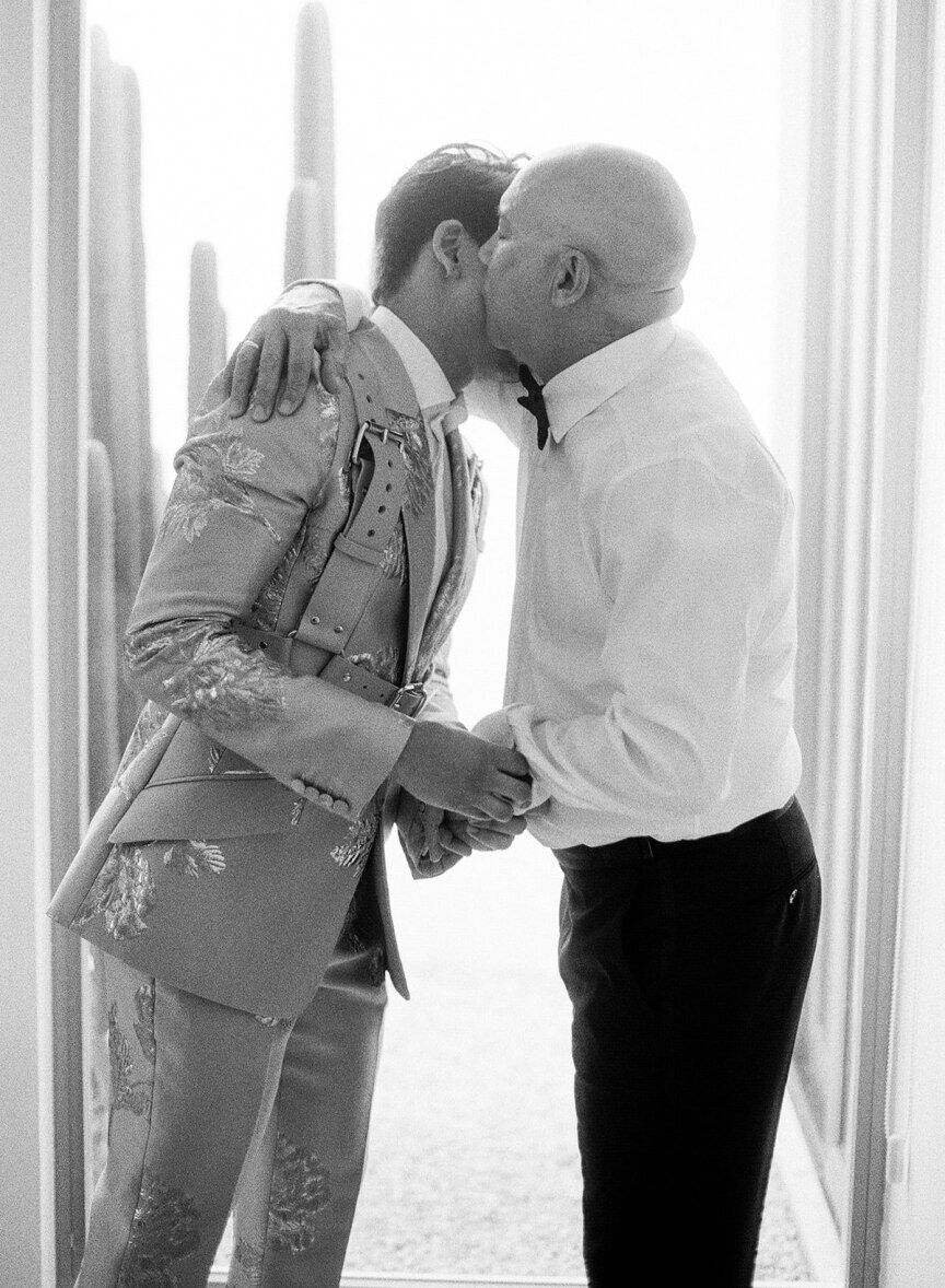 First Look Photos: A father kisses his son on the cheek on his wedding day.