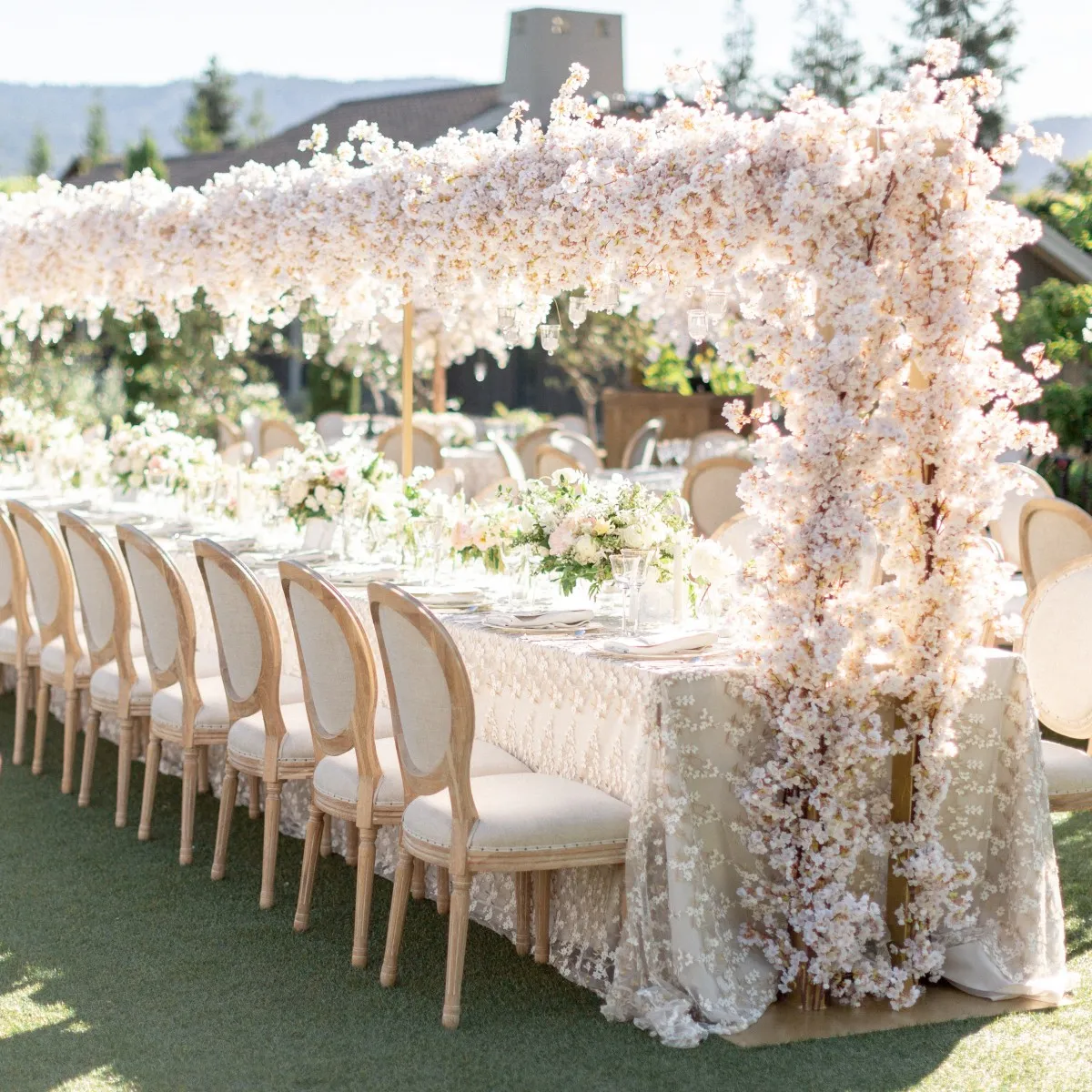 Hanging wedding decorations and a flower chandelier: Light pink floral installation over long wedding reception table