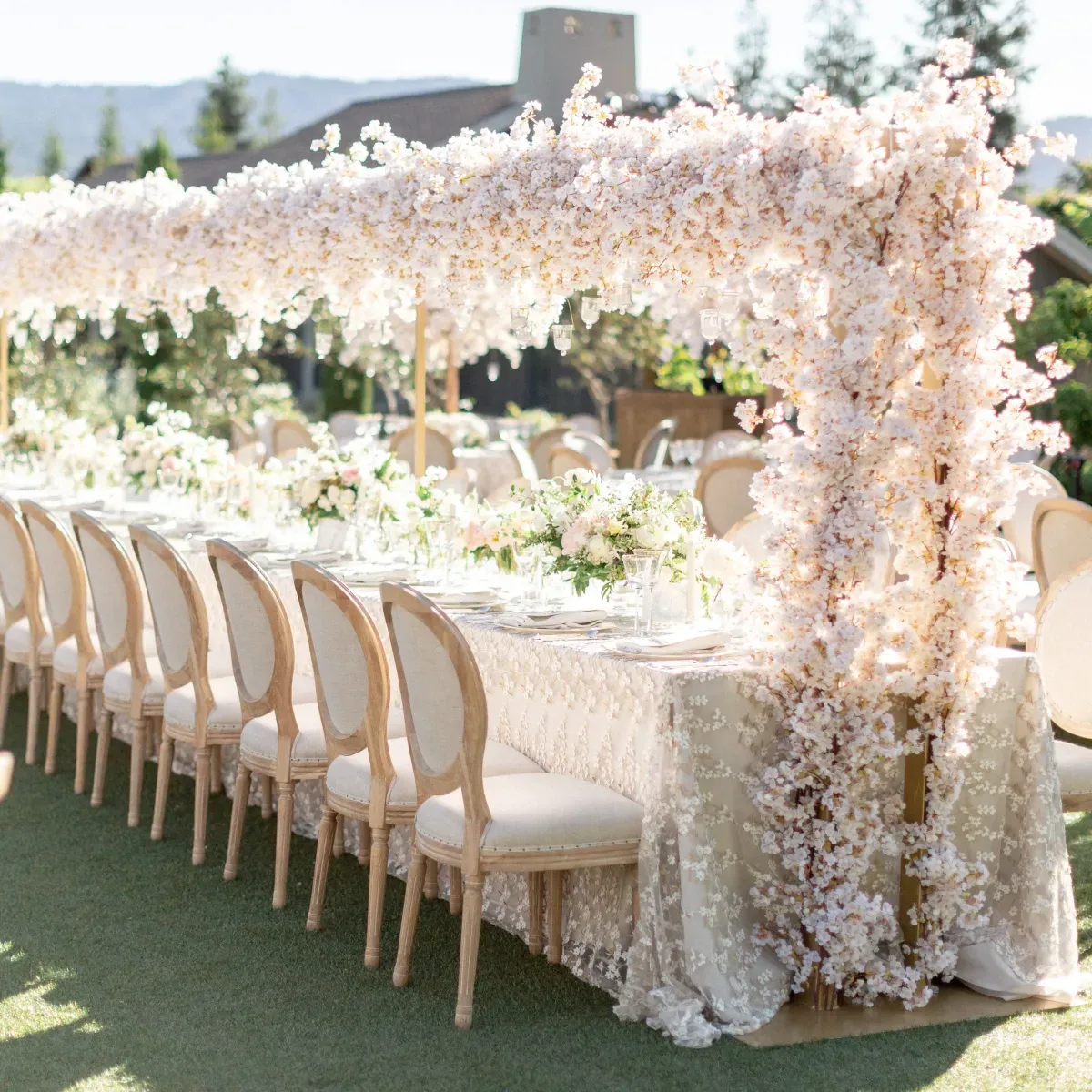 Hanging wedding decorations and a flower chandelier: Light pink floral installation over long wedding reception table