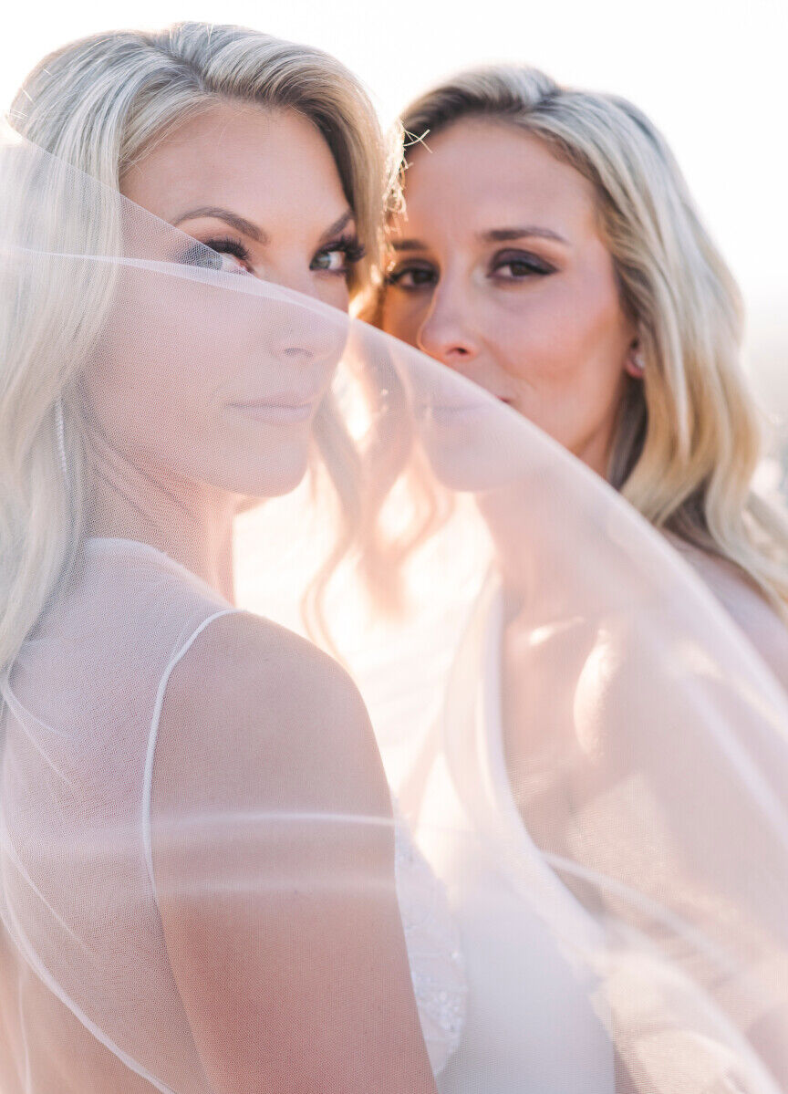 Wedding couple posing for portrait behind their wedding veil.