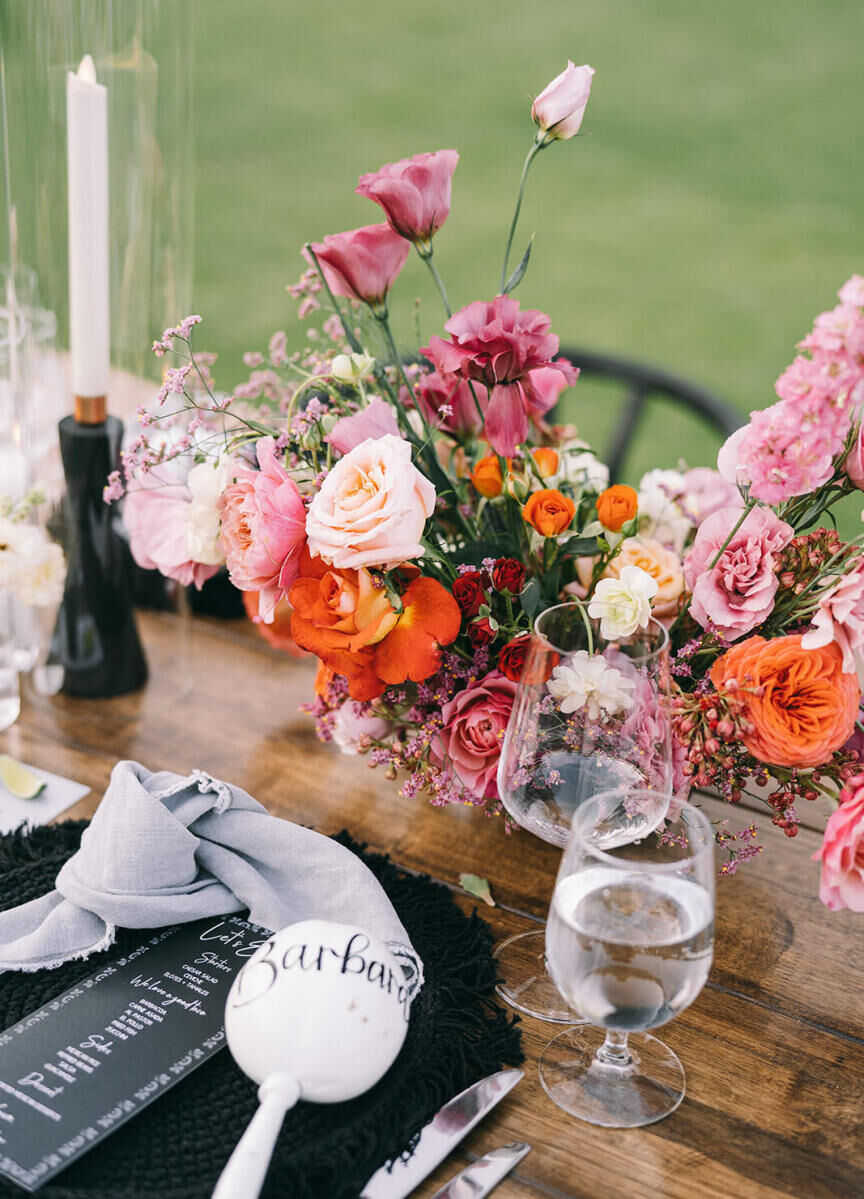 Colorful floral centerpieces popped against the otherwise black and white table at a glam beach wedding reception in Mexico.