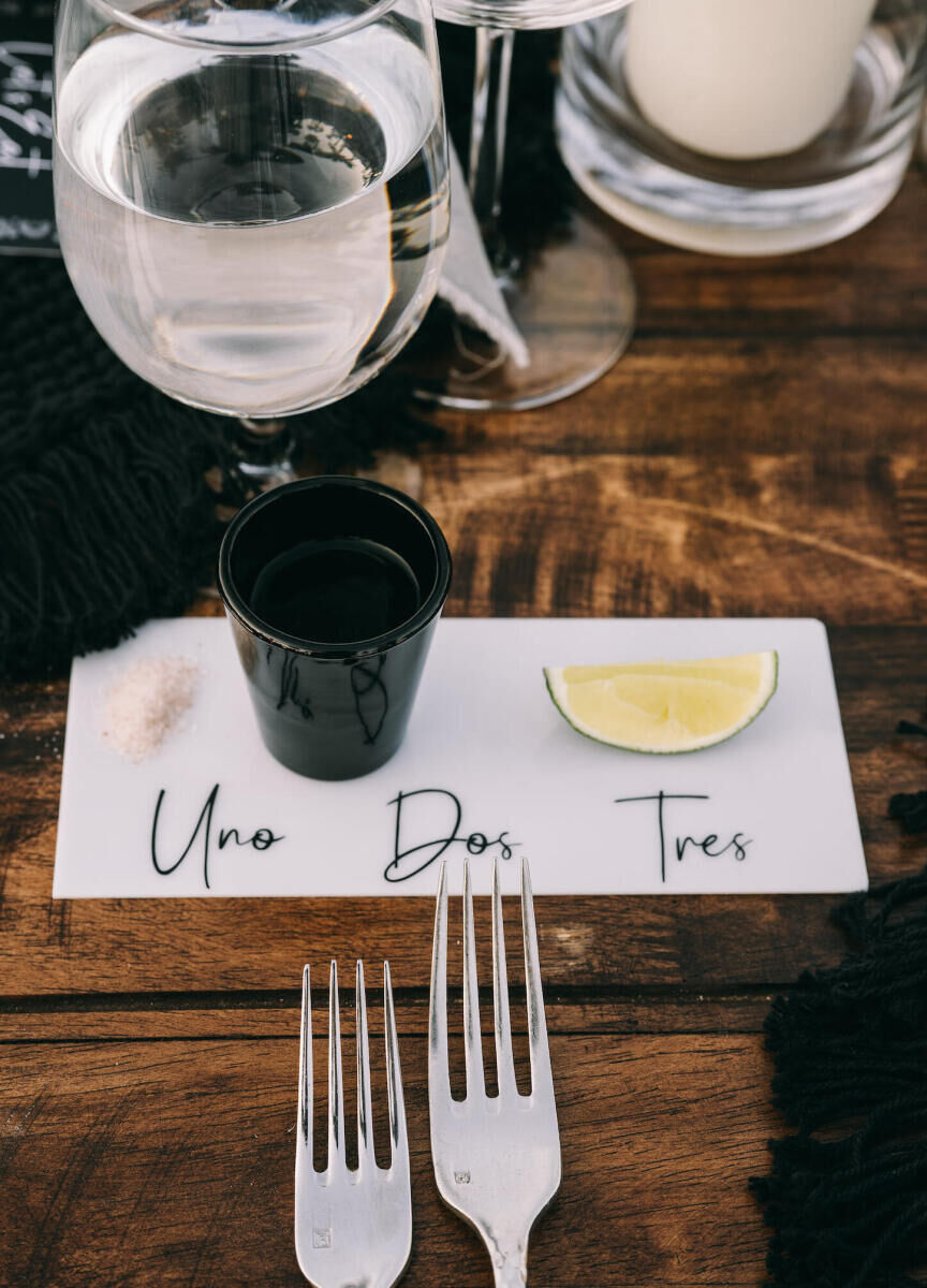 During a glam beach wedding reception, each guest was treated to a tequila shot set out for them at their place setting, with calligraphed 