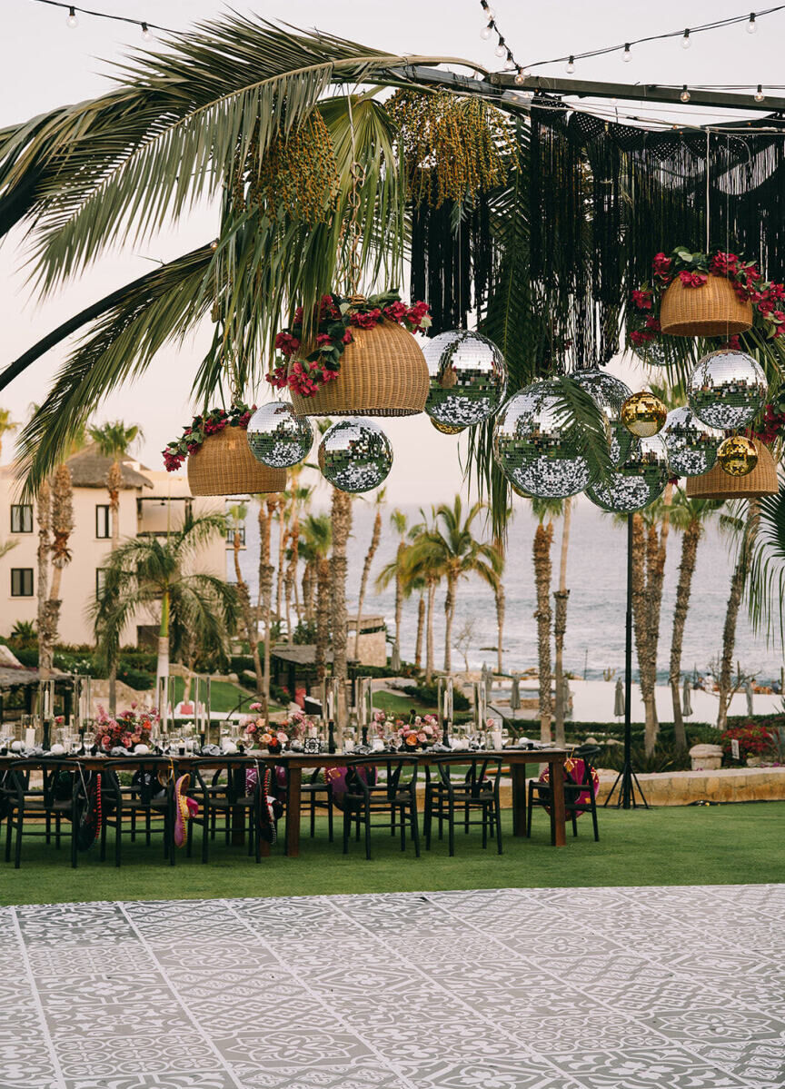 Disco balls, palms, and bougainvillea hung over a faux-tiled dance floor during a glam beach wedding reception in Mexico.