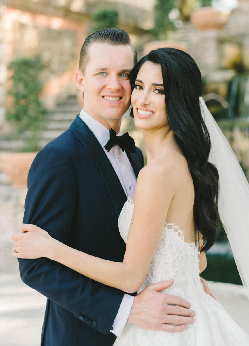 A groom and bride embrace and pause for a portrait during their glam, garden wedding.